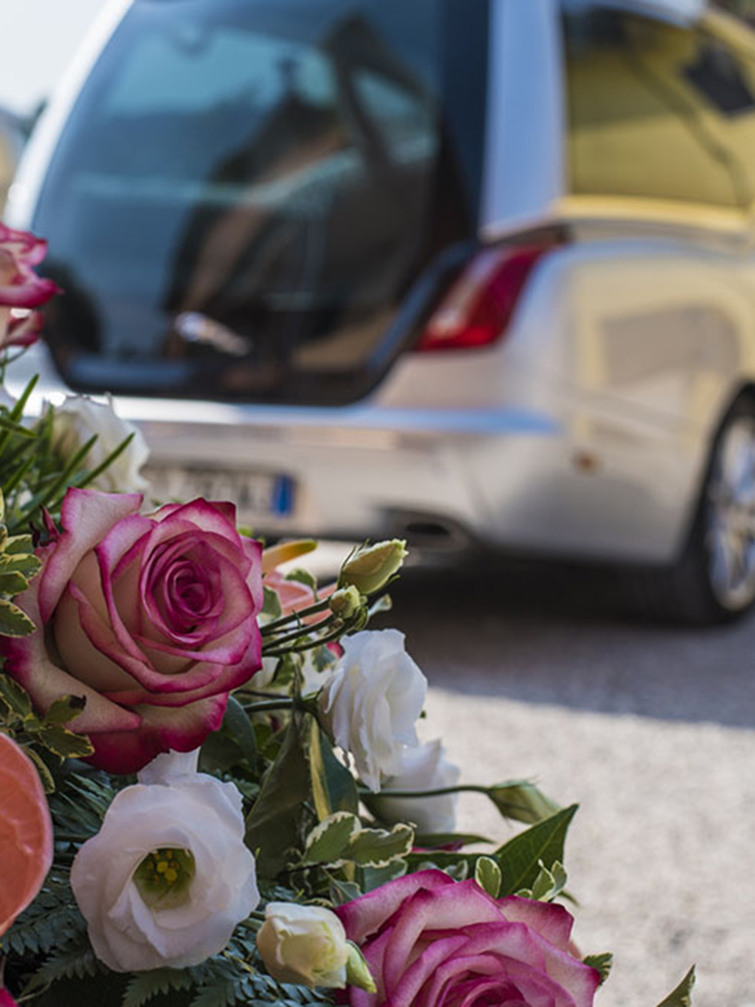 Dettaglio di fiori funebri con carro funebre sullo sfondo sfocato